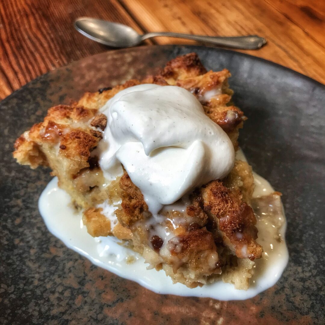 A piece of apple pie on a plate with whipped cream.