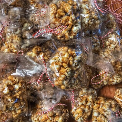 Caramel popcorn in bags on a wooden table.