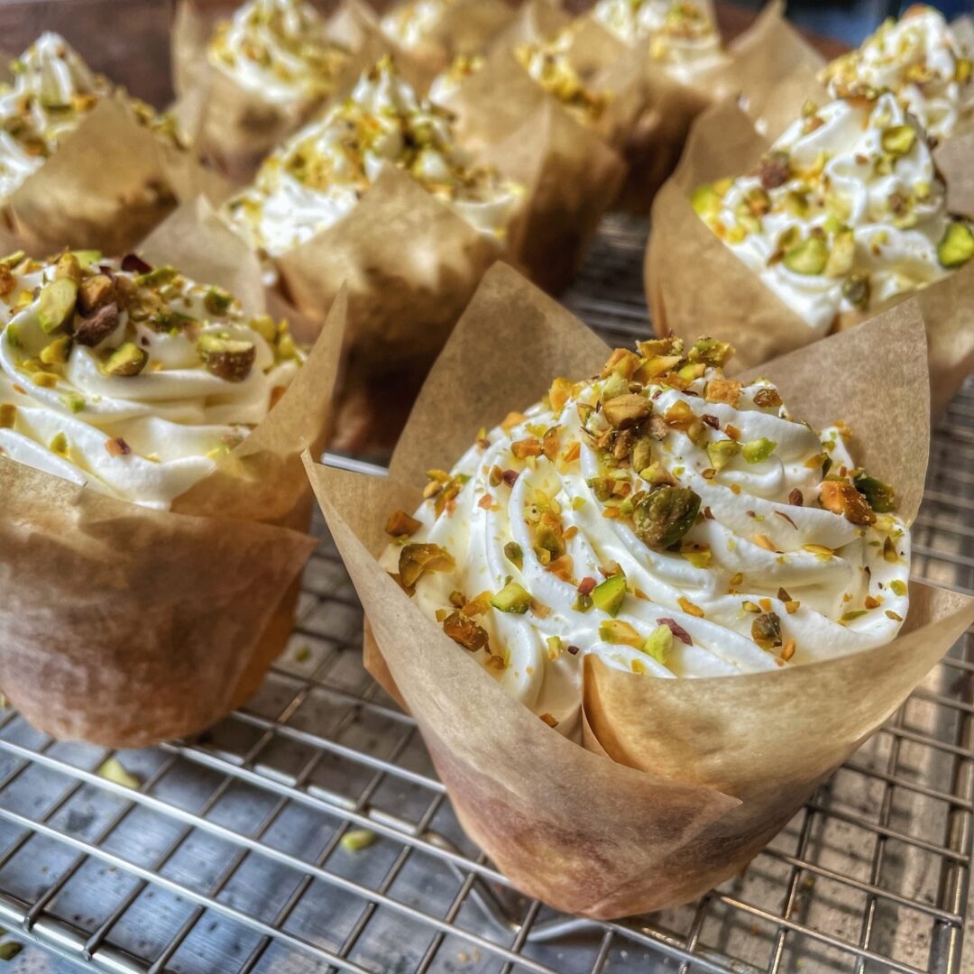 Pistachio cupcakes with whipped cream and pistachios.