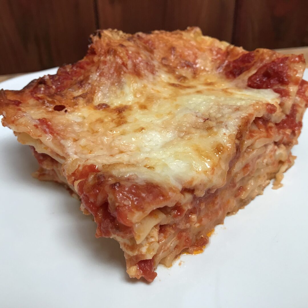 A slice of lasagna on a white plate.