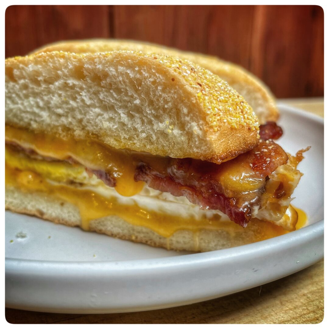 A sandwich with bacon, eggs and cheese on a plate.