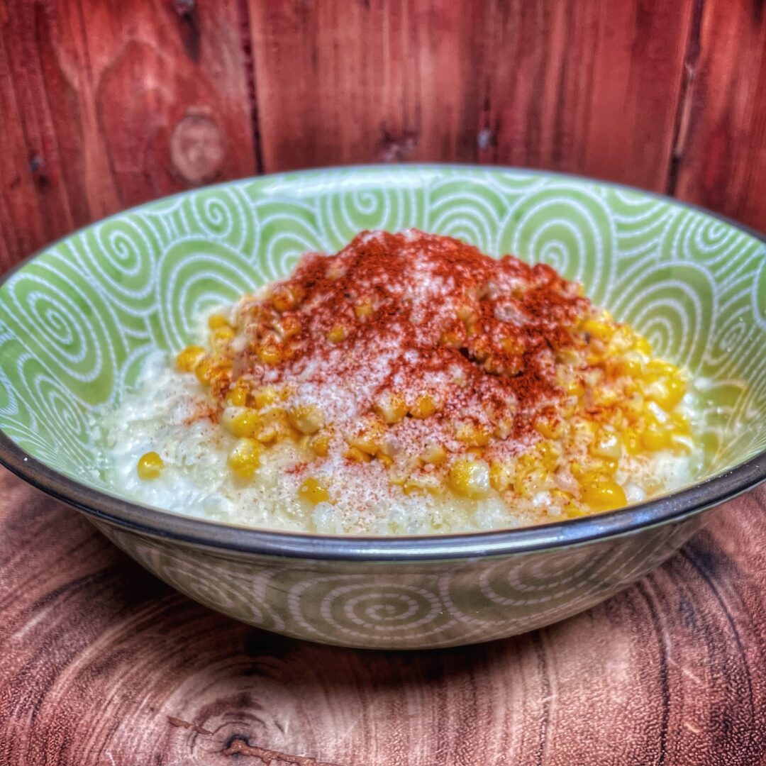 Corn on the cob in a bowl on a wooden table.